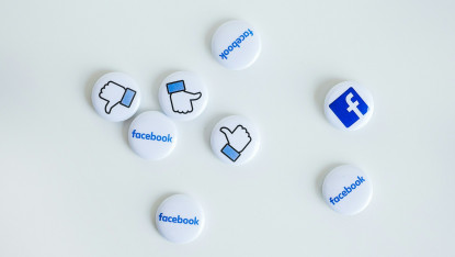 Scattered white buttons with Facebook logos, thumbs-up, and thumbs-down icons on a white background, conveying social media interaction and opinion.